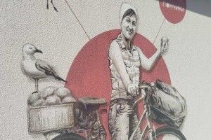 Жінка стоїть з велосипедом і гукає: «Свіжі пончики!» - на Світязі з'явився мурал Юрія Чайки