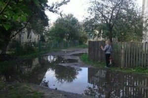 Вулицю залило так, що пройти можна лише ступаючи одною ногою й тримаюсь за огорожу (Фото)