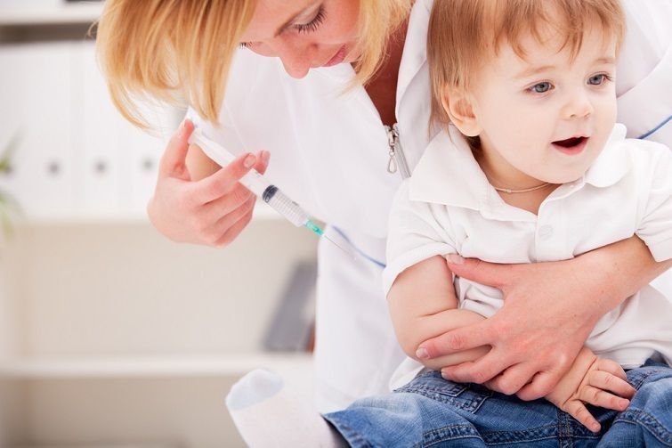 Doctor giving a child injection in arm