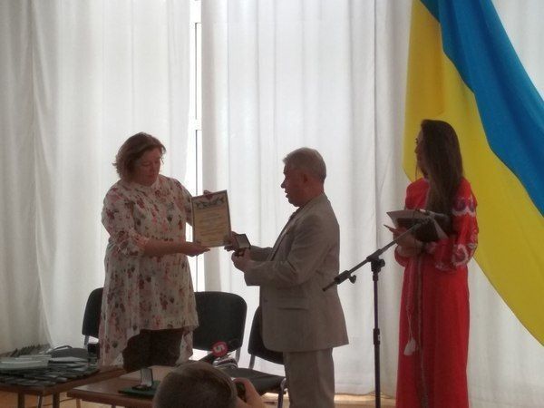 Син начальника штабу УПА-Південь Василя Проюцка Микола передає генеральному директорові НМІУ Тетяні Сосновській Холотий хрест бойової заслуга свого батька.