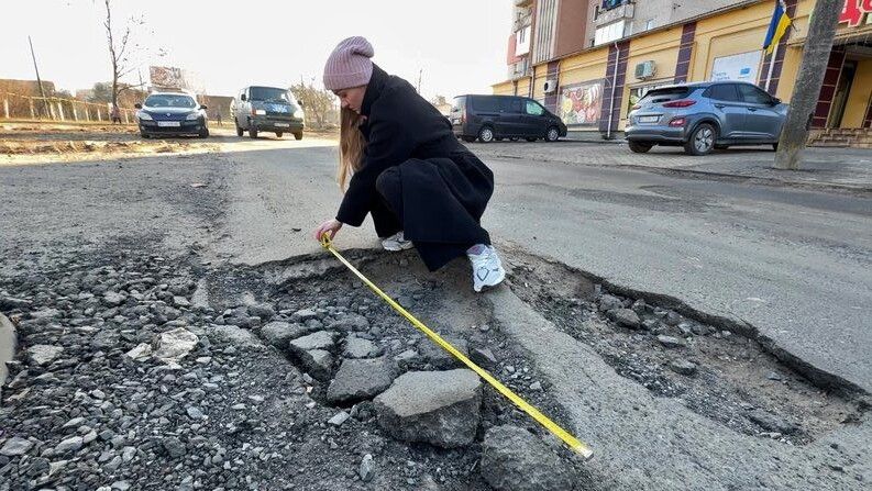 Кореспондентка Анна Романчук проводить заміри утвореної вибоїни. 